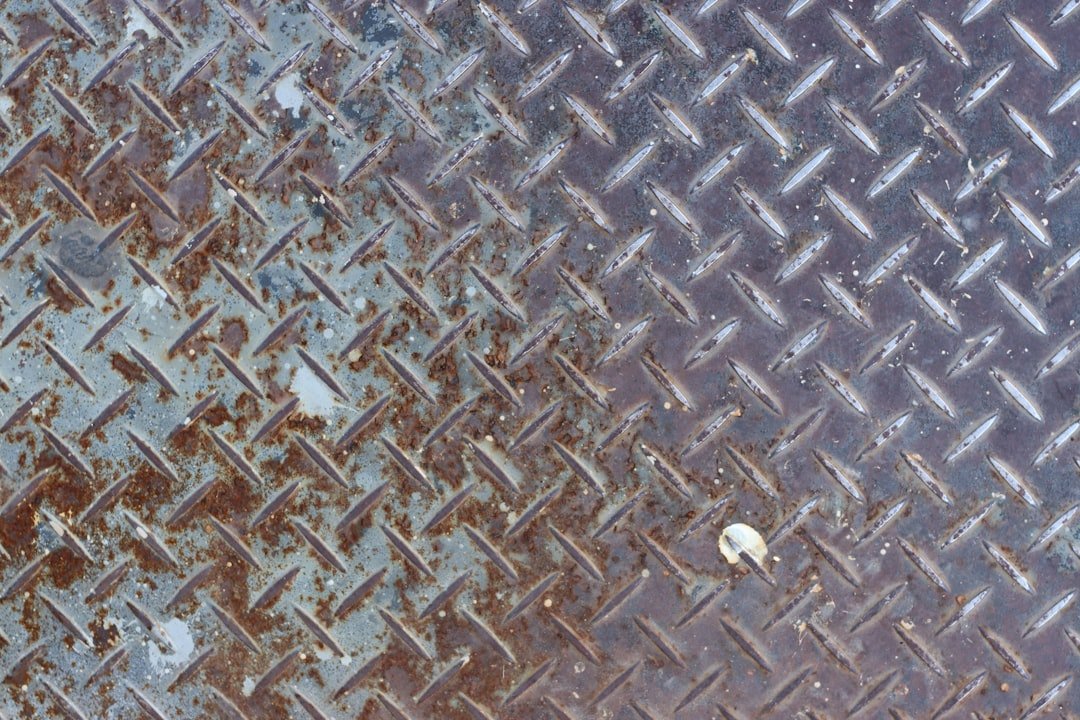 Steel plate with weld bead surrounded by heavy spatter deposits requiring post-weld cleanup
